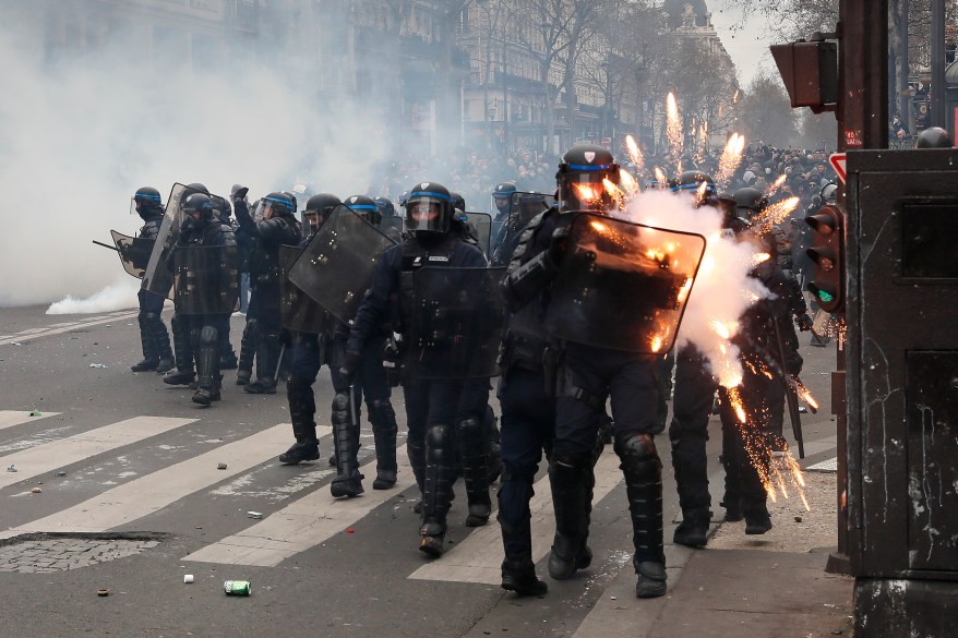 Riot police are struck by fireworks during violent clashes over the government's reform of the pension system on March 23, 2023 in Paris, France.