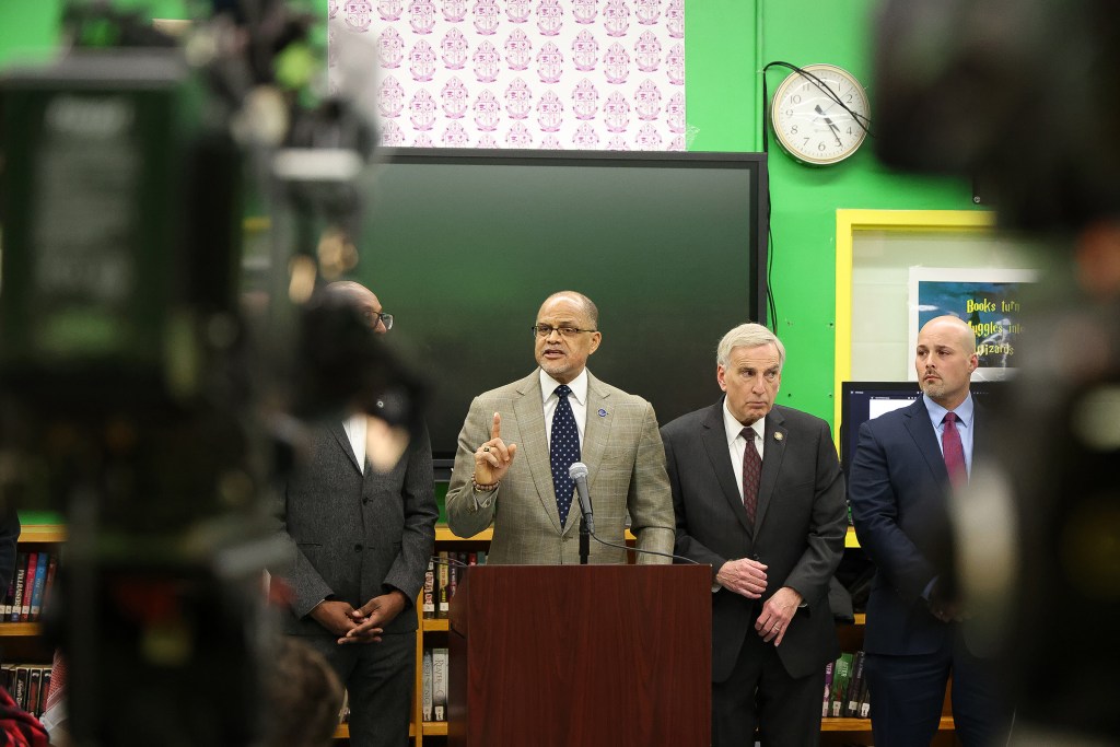 Schools Chancellor David Banks speaks at podium with government and UFT officials.