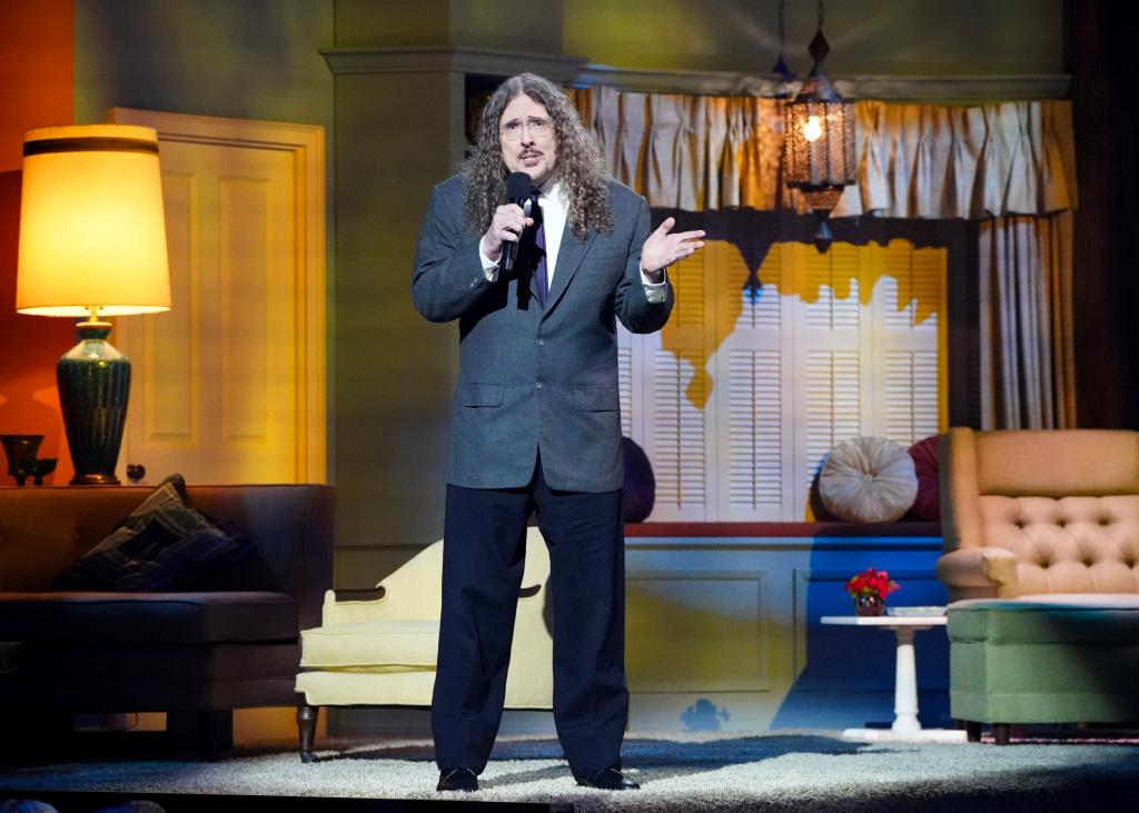 Weird Al sings the theme song to "The Dick Van Dyke Show" on its replicated set. There is a table lamp to his left that is from the original series.