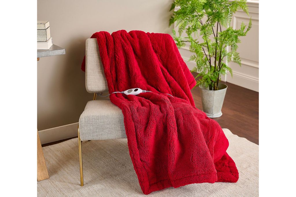 A red blanket on a chair with an attached remote