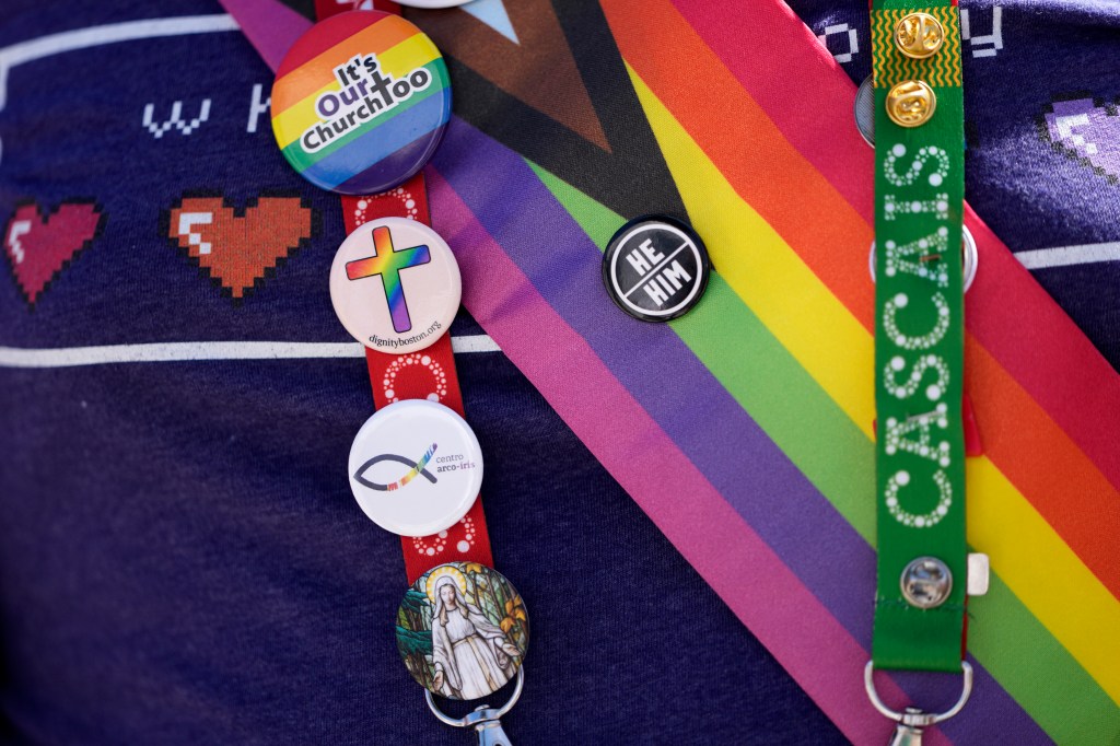 A representative of Dignity USA, a group of LGBTQ+ Catholics, wears pins on the lanyard of his pilgrim credential, outside the Sao Vicente de Paulo Parish Social Center, after Pope Francis visited it, in the Serafina neighbourhood of Lisbon, Friday, Aug. 4, 2023.