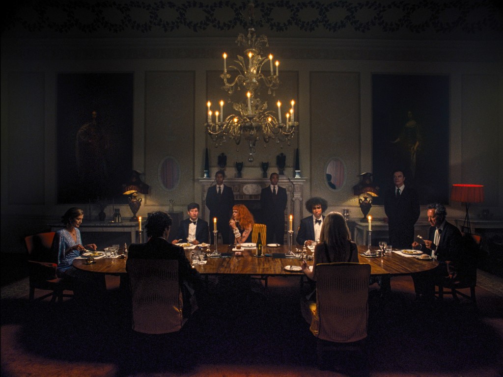 Rosamund Pike, Jacob Elordi, Barry Keoghan, Carey Mulligan, Archie Madekwe, Alison Oliver sitting around a table. 