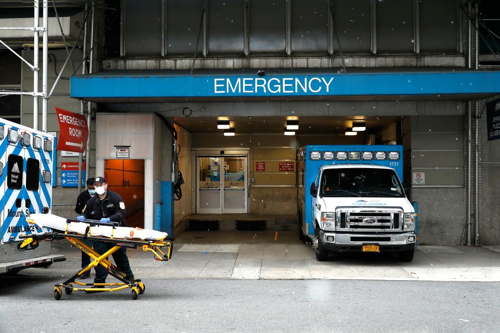 Emergency Medical Technicians move a gurney out of the emergency entrance into an ambulance at Mt. Sinai-Beth Israel Hospital amid coronavirus crisis. 