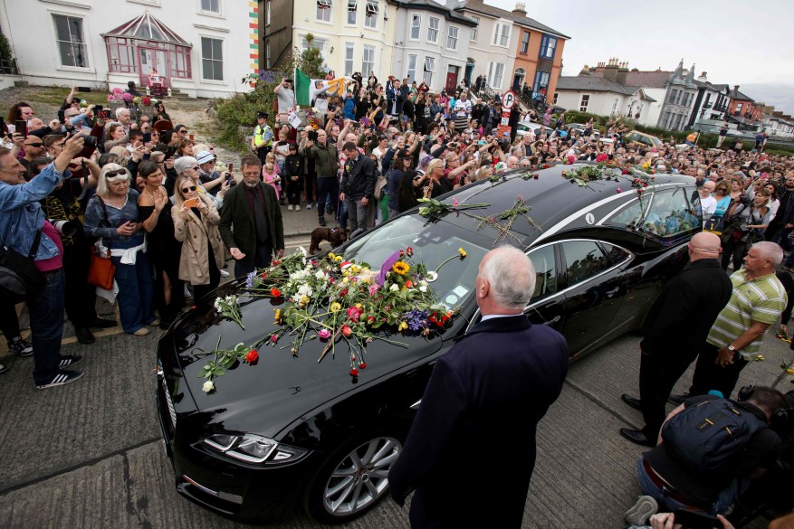 People lay flowers and tributes on the hearse during the funeral procession of late Irish singer Sinead O'Connor, outside her former home in Bray, eastern Ireland, ahead of her funeral on Aug. 8, 2023.