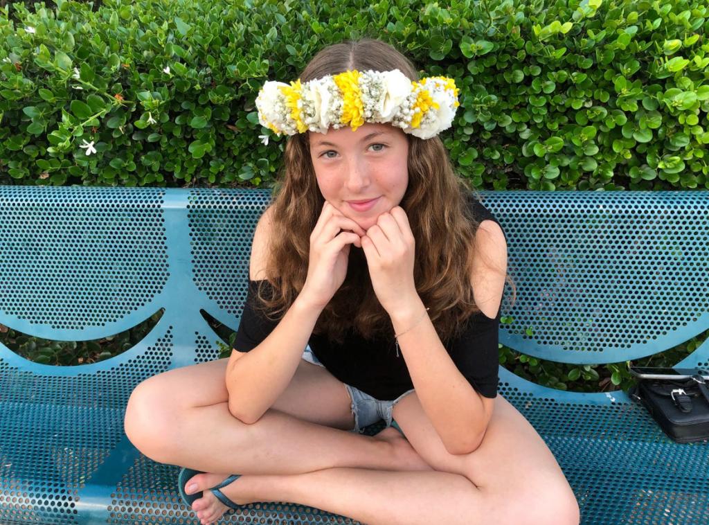 Naama Levy sitting on a bench wearing a floral arrangement in her hair