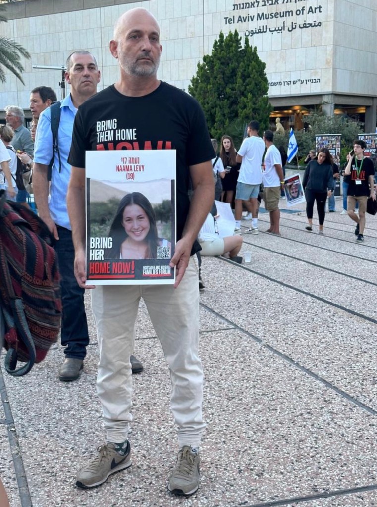 Yoni Levy holding a poster of his daughter Naama in a square in Tel Aviv