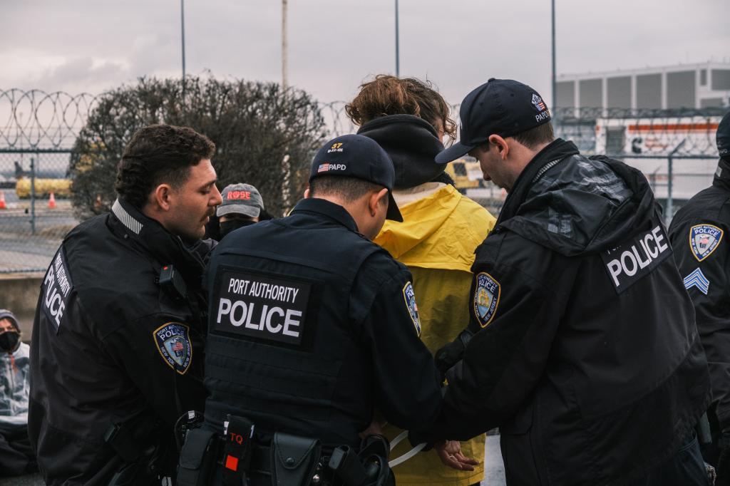 Port Authority Police officers detain one of protestors involved in Wednesday's traffic blocking event near JFK Airport.