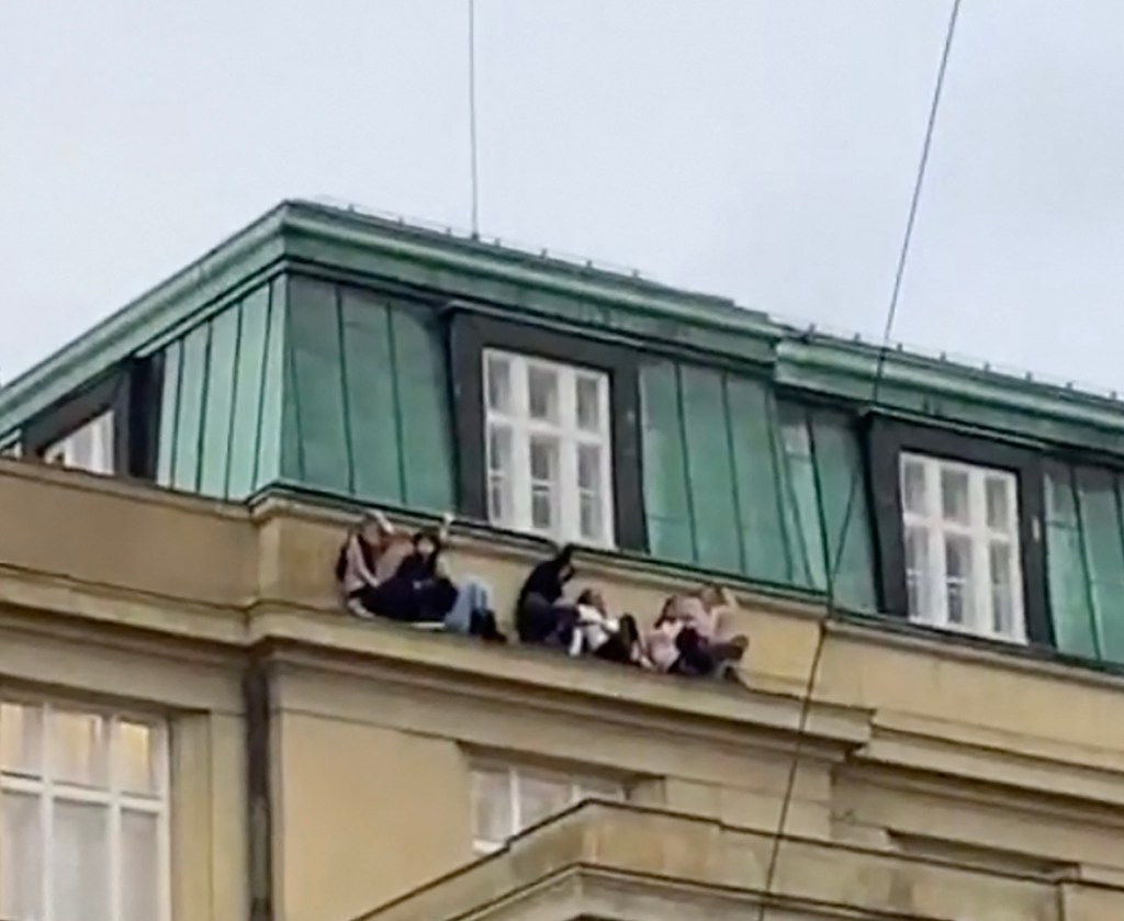 Students are seen hiding on a rooftop ledge during a mass shooting