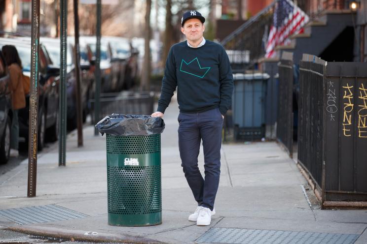 Sean Feeney leaning on a green garbage can painted with the words "Clean Streets"