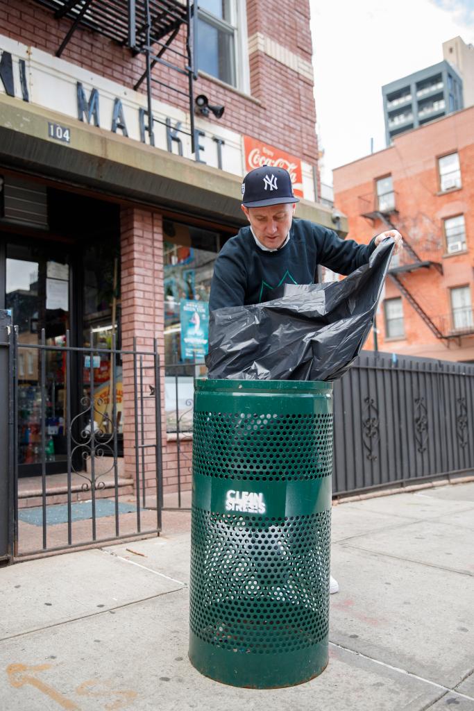 Sean Feeney adds a garbage bag to one of his green garbage bins.