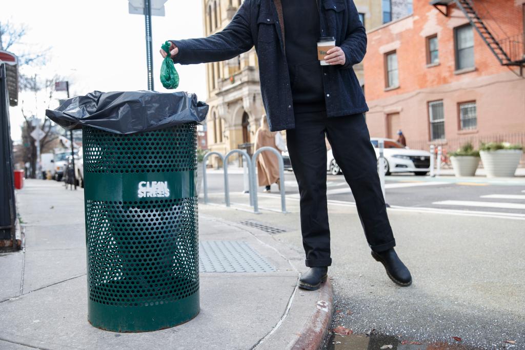 A dog owner drops a bag of dog waste into one of Fini's garbage cans.