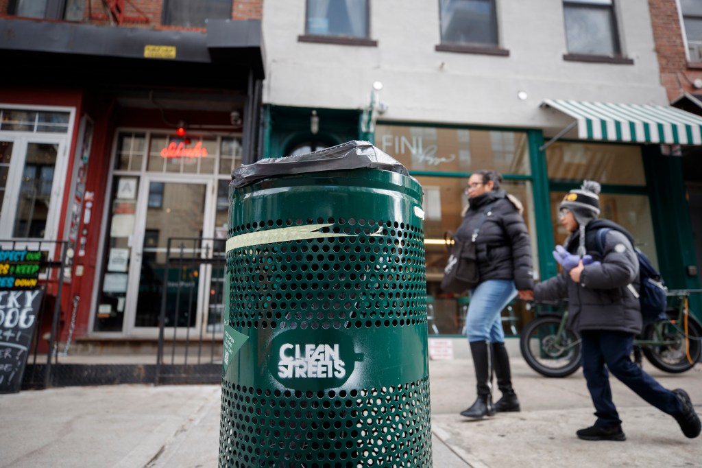 One of the green trash cans that stands outside of Fini Pizza.