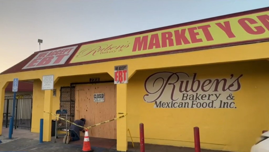 A worker puts up a wood panel as a temporary barricade to block anyone making entrance into the store following Tuesday's looting.