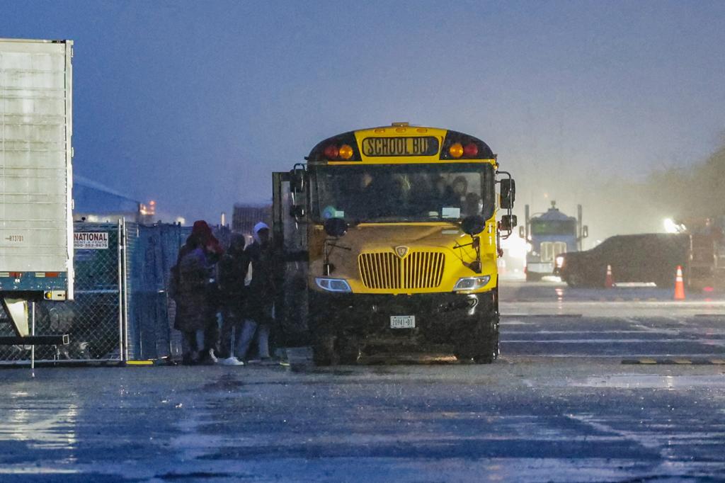 NYC School Buses evacuate migrants at the migrant camp inside Floyd Bennett Field before a storm rolls in.