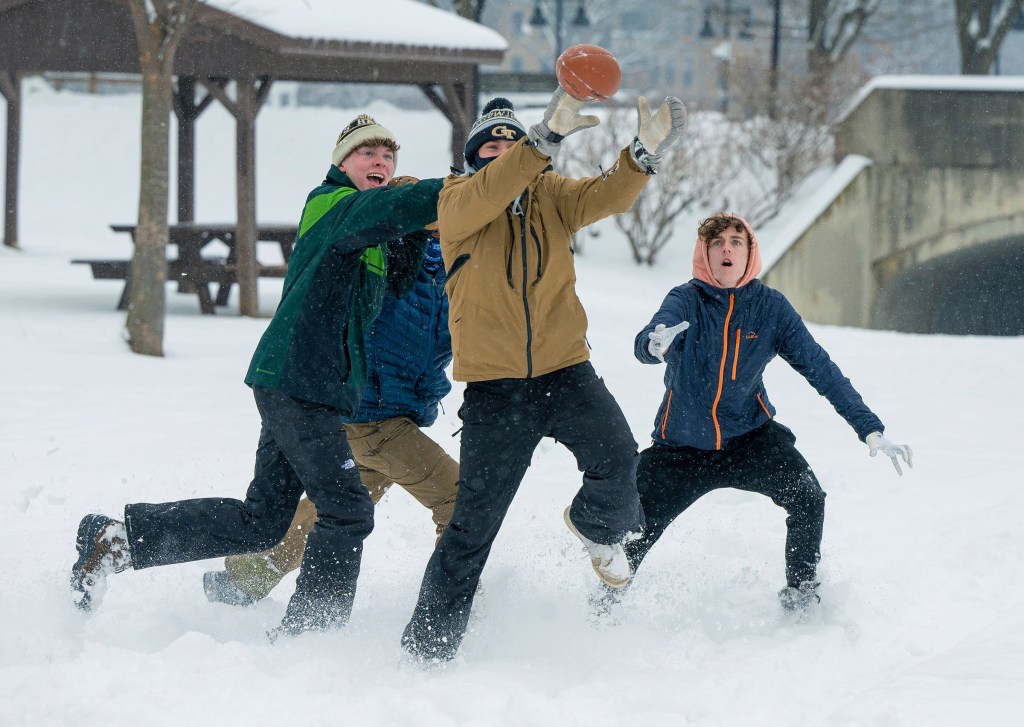 Friends play football in the snow at Baker Park on Jan. 19, 2024, in Frederick, Maryland.