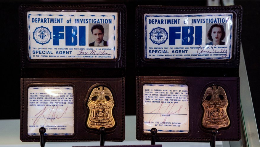 Badges, including David Duchovny's character's badge, on a shelf.