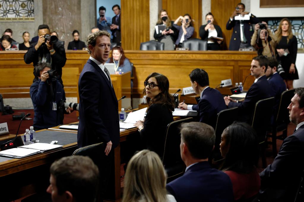 Mark Zuckerberg, CEO of Meta, speaks at a Senate Judiciary Committee hearing with people in the background.