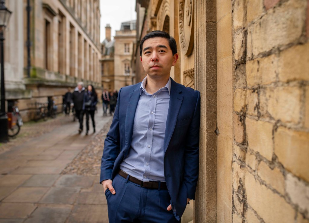 Rob Henderson leans against a wall outside at Cambridge campus.