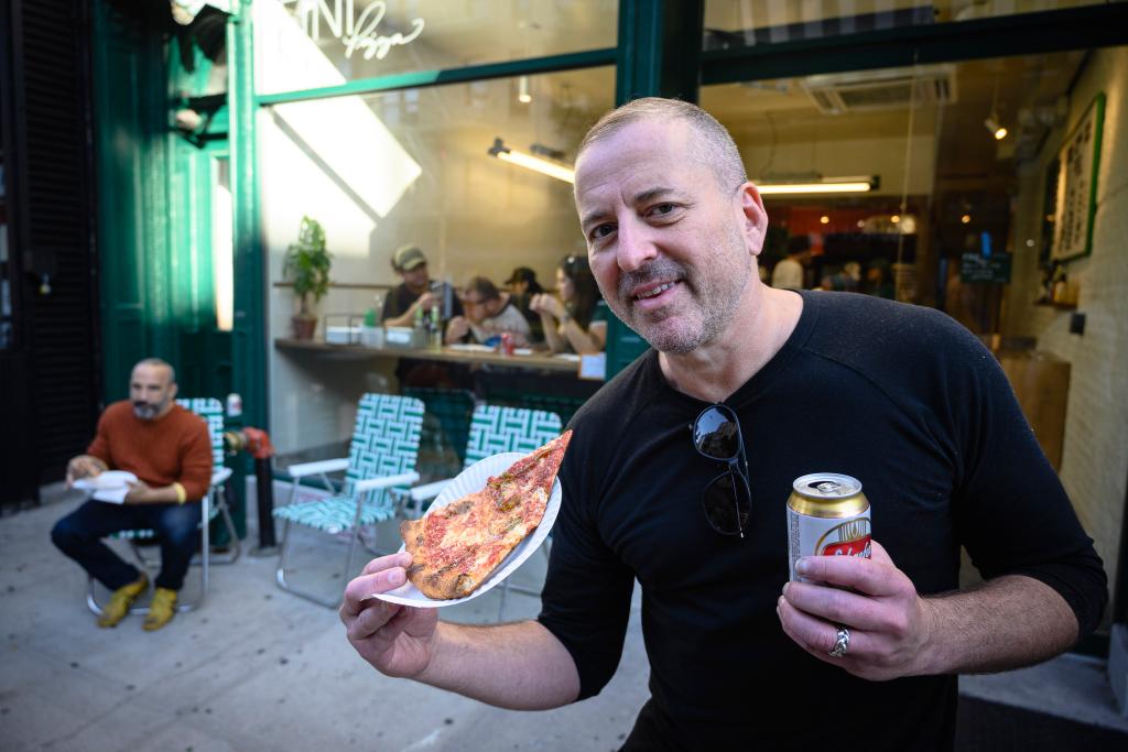 A customer holds a slice outside of Fini.