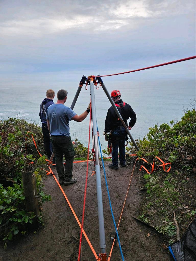 Rescuers stand ready to repel down the cliff.