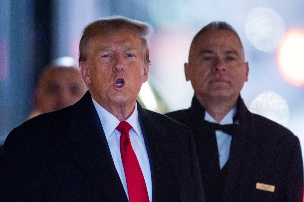 Donald Trump in a suit and tie departing Trump Tower in New York, surrounded by supporters and security personnel.