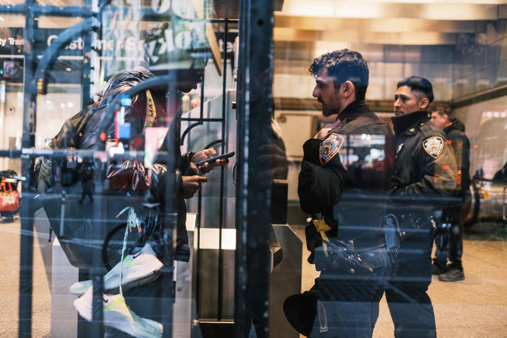 A NYPD officer talks to a person trying to get through the exit gate at the Times Square subway station. 