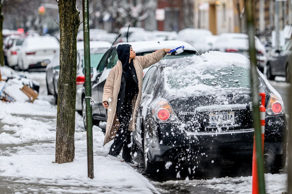  A person clears snow from a car in the Crown Heights Neighborhood of Brooklyn.