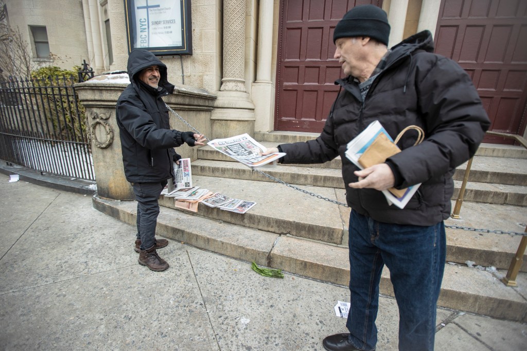 Sadik Topia selling someone a newspaper