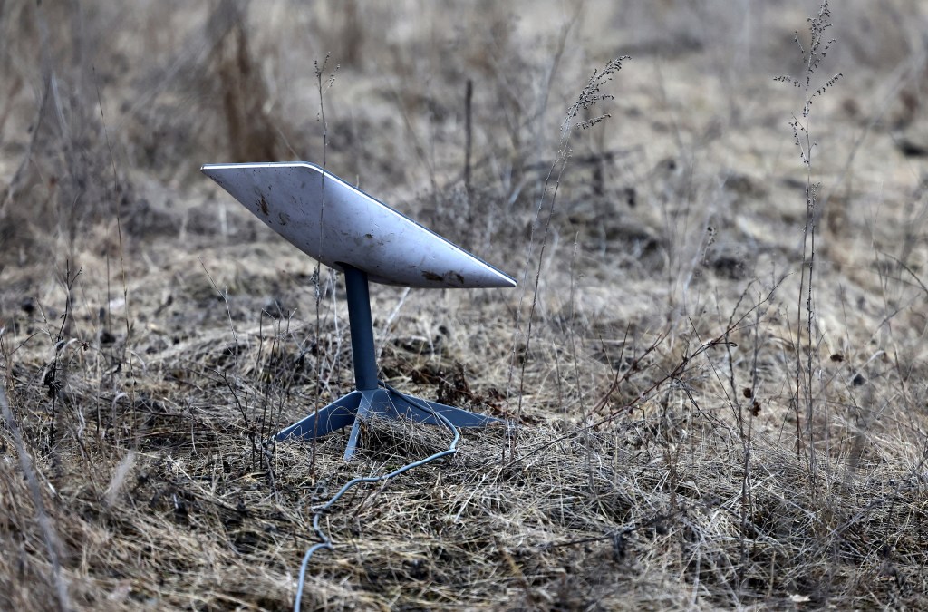 A Starlink satellite internet system set up on grassland.