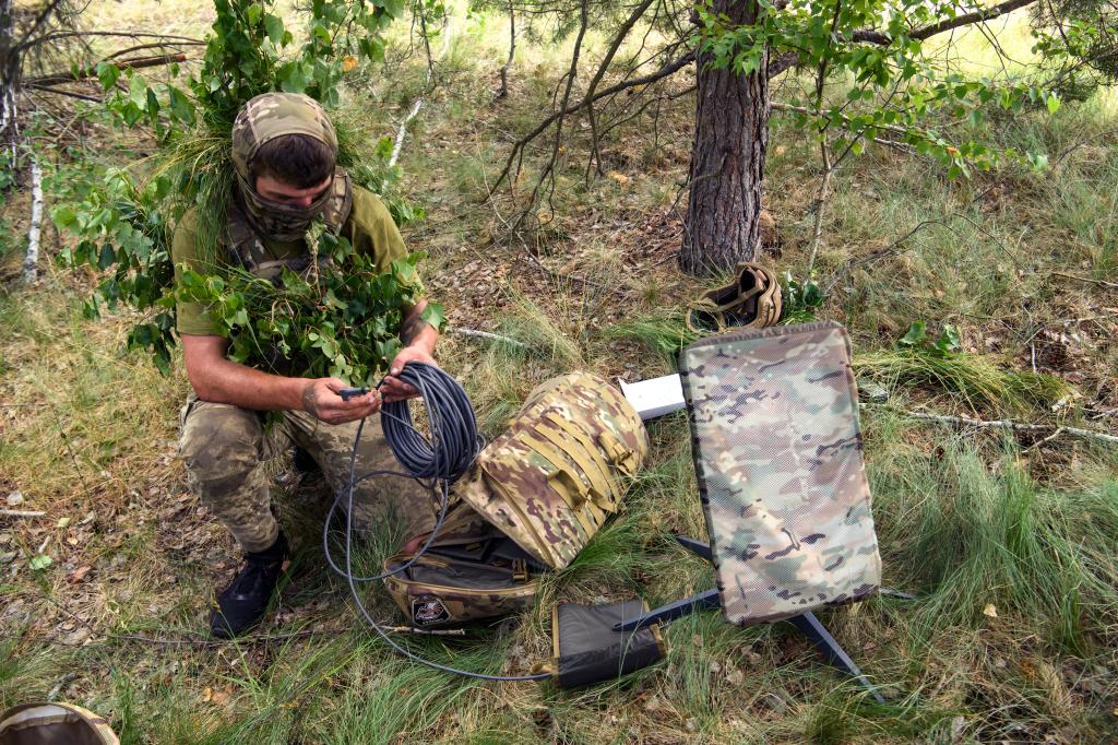 Ukraine soldier tends to Starlink satellite.