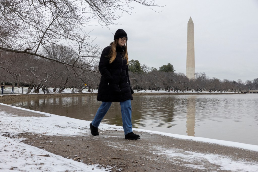 A woman walks around the Tidal Basin with the Washington Monument standing in the distance in Washington, D.C., U.S., January 15, 2024. 