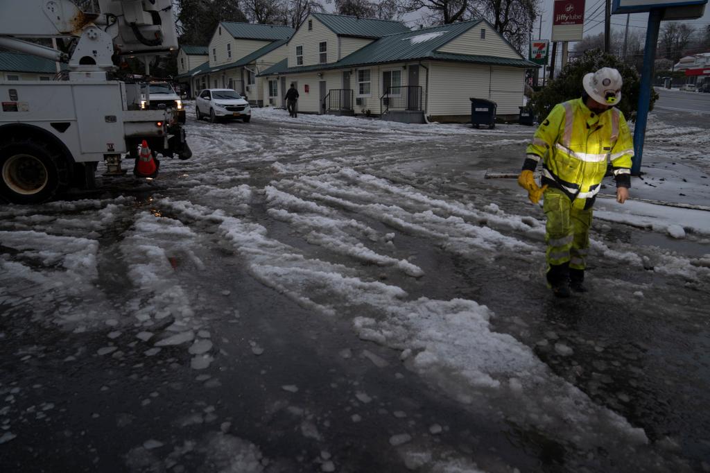 A worker with International Line Builders Inc. walks through melting snow and ice as freezing rain falls to help crew members turn the power back on Thursday, Jan. 18, 2024, in Portland, Ore. 