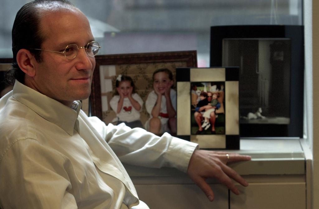 Lutnick sits at his desk with pictures o family and friends, including those who died on 9/11, visible.