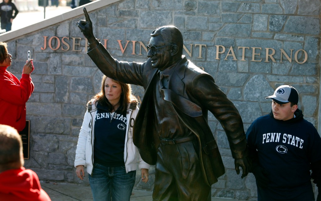 Fans get in place for a photo with a statue of former coach Joe Paterno at Penn State's Beaver Stadium before their game with the University of Nebraska