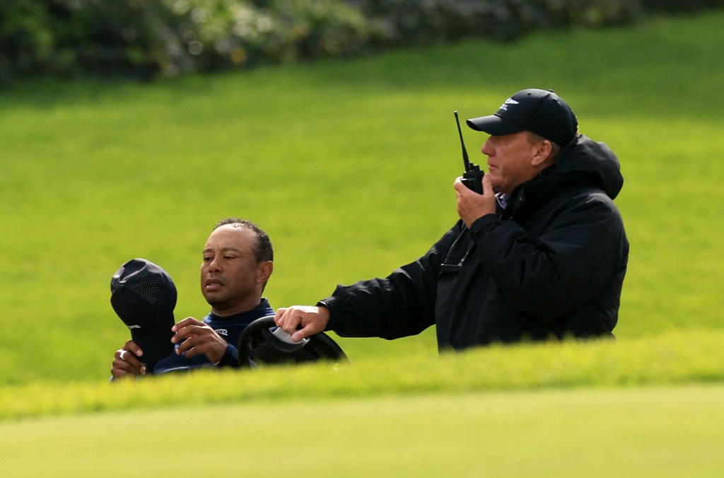 Tiger Woods of the United States speaks with a rules official after withdrawing from the tournament due to illness on the sixth hole during the second round