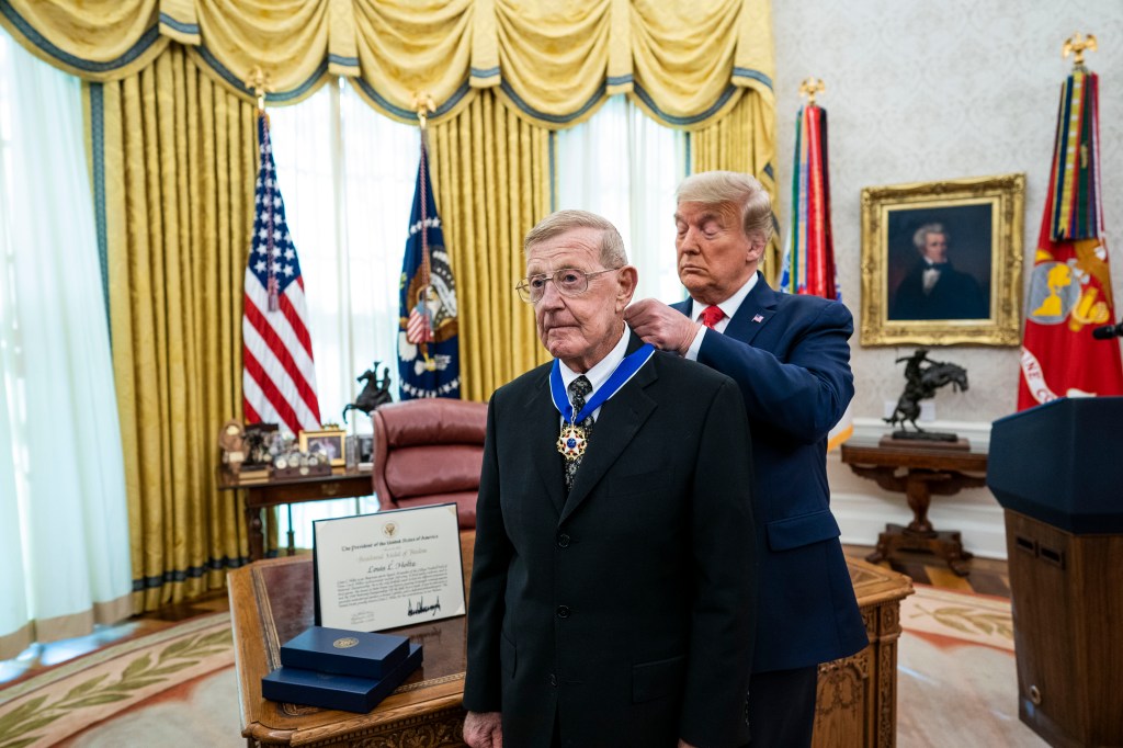  President Donald Trump presents the Medal of Freedom to former college football coach Lou Holtz in the Oval Office of the White House on December 3, 2020.