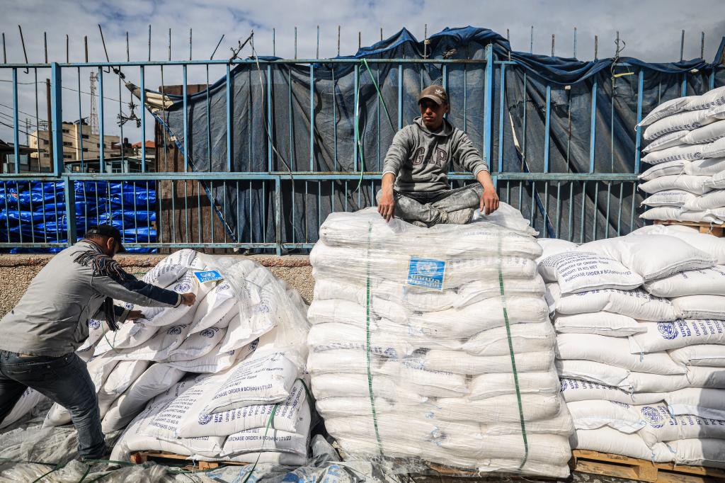 A worker rests as displaced Palestinians receive food aid at the United Nations Relief and Works Agency for Palestine Refugees (UNRWA) center in Rafah in the southern Gaza Strip on January 28, 2024, amid ongoing battles between Israel and the Palestinian militant group Hamas. Israel has alleged several UNRWA staff were involved in Hamas's October 7 attack, leading some key donor countries to suspend funding and the agency to fire several staff over the claims, in a row between Israel and UNRWA a day after the UN's International Court of Justice ruling on January 26 that Israel must prevent possible acts of genocide in the conflict and allow more aid into Gaza. (Photo by AFP) (Photo by -/AFP via Getty Images)