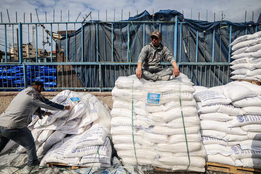 A worker rests as displaced Palestinians receive food aid at the United Nations Relief and Works Agency for Palestine Refugees (UNRWA) center in Rafah in the southern Gaza Strip on January 28, 2024, amid ongoing battles between Israel and the Palestinian militant group Hamas. Israel has alleged several UNRWA staff were involved in Hamas's October 7 attack, leading some key donor countries to suspend funding and the agency to fire several staff over the claims, in a row between Israel and UNRWA a day after the UN's International Court of Justice ruling on January 26 that Israel must prevent possible acts of genocide in the conflict and allow more aid into Gaza. (Photo by AFP) (Photo by -/AFP via Getty Images)
