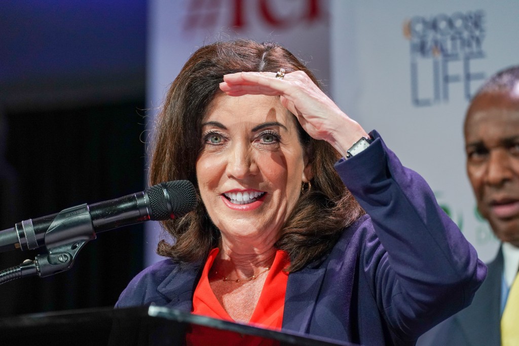 Kathy Hochul speaking into a microphone at a church in Harlem, about allocating funds for healthcare access.