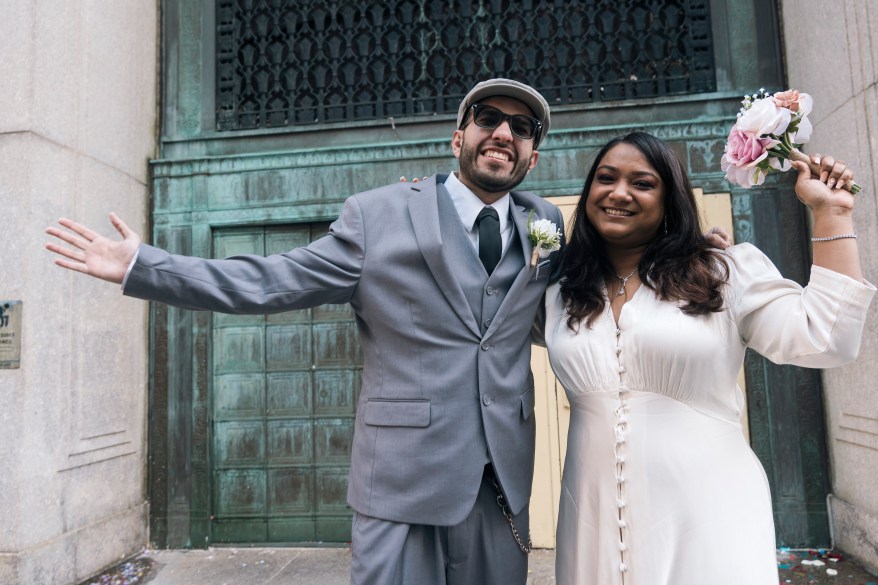 Newlyweds posing for a photo outside of the Office of the City Clerk.