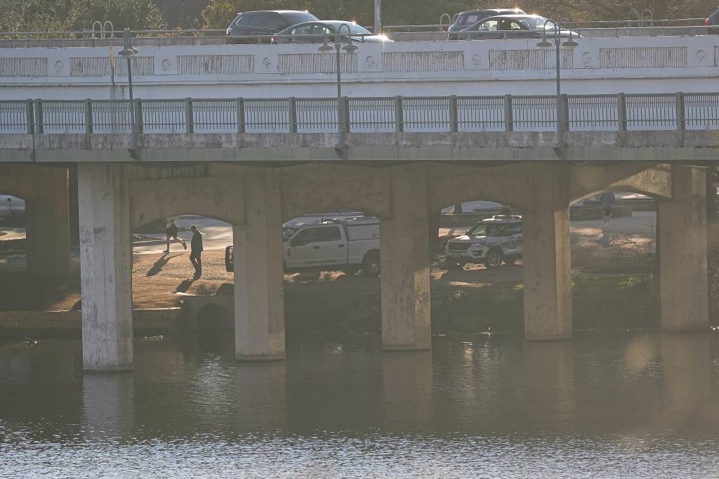 Austin Police Department crime scene investigation vehicles work underneath the First Street bridge on the opposite bank from where APD responded to a report of a body in Lady Bird Lake near Downtown Austin on Monday, Feb. 5, 2024.