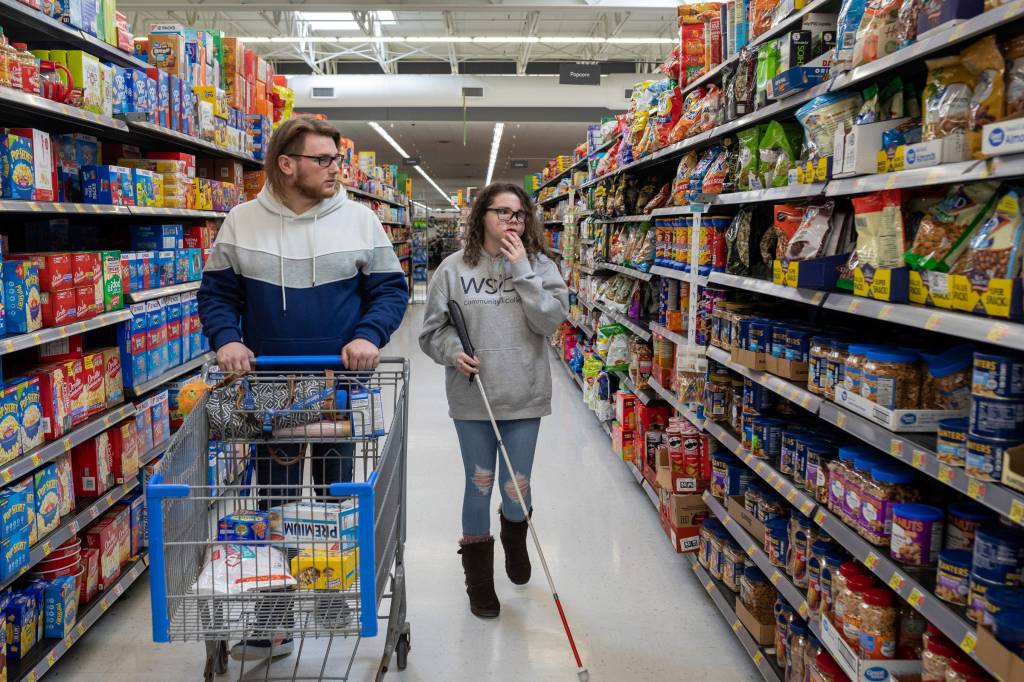 Charles Austin, 21, pushes a shopping cart down an aisle of process food items beside his girlfriend, Amedy Dewey, 24, inside Walmart in Ludington.