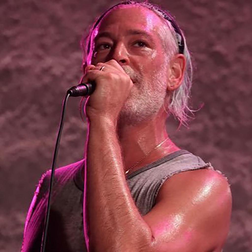A close-up of Matisyahu singing into a microphone during a cancelled concert due to safety concerns and staff shortage at a venue in Southern Arizona.