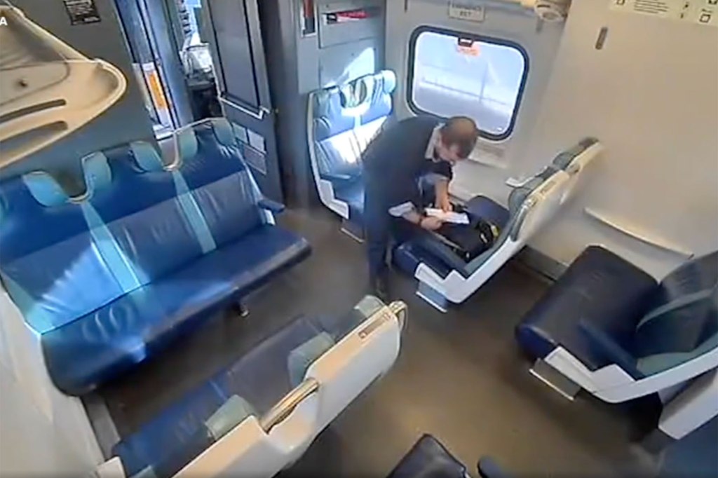 A surveillance image of an LIRR conductor discovering a bag full of cash left behind by a passenger.