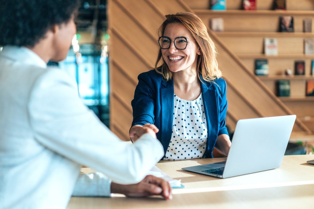 Two people shaking hands in a business meeting in a modern office, discussing a new project and corporate team on board room.