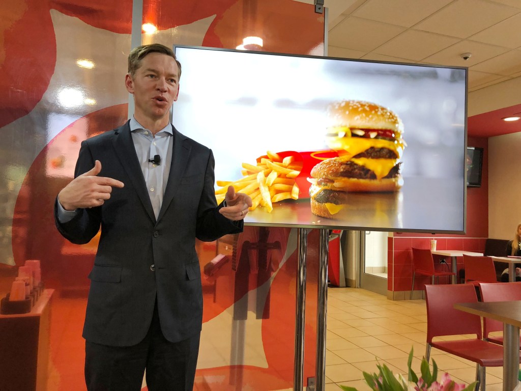 Chris Kempczinski giving a speech in front of a screen at a McDonald's event in Oak Brook, IL, USA.