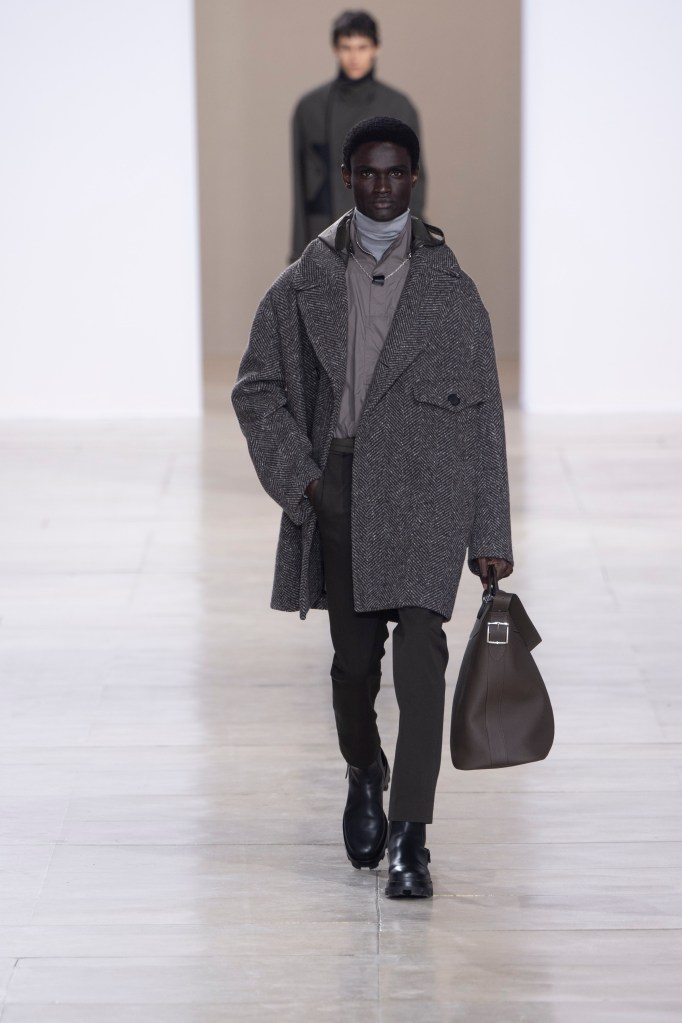 A model in a herringbone jacket on the runway