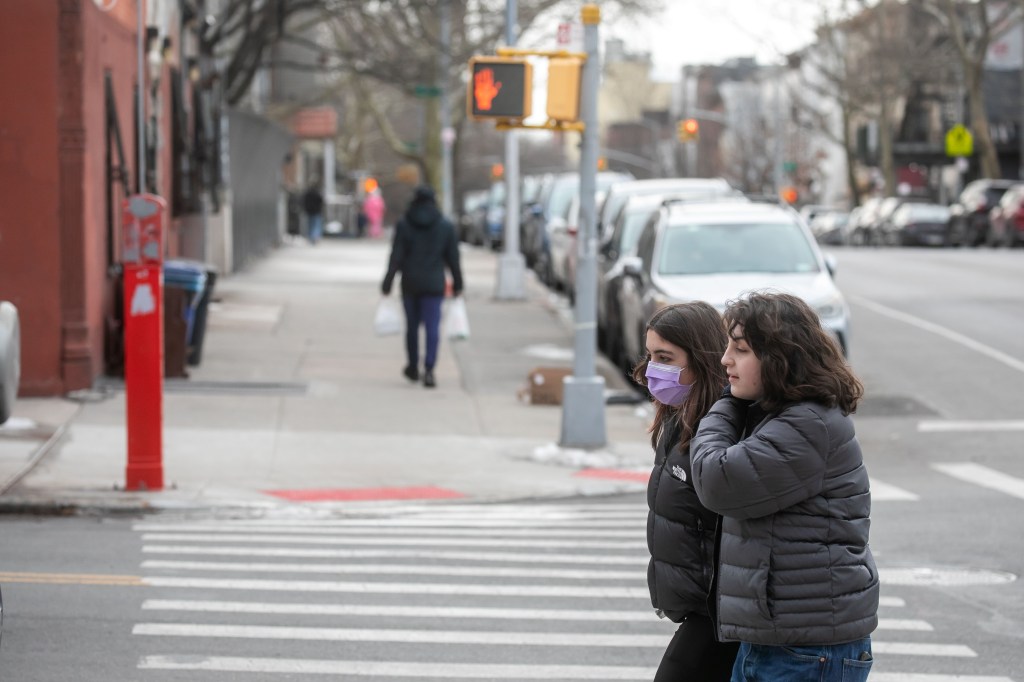 Pedestrians pass the corner of 6th Avenue and Prospect Avenue, Brooklyn, New York where a bad smell arises, on a street with two masked women.