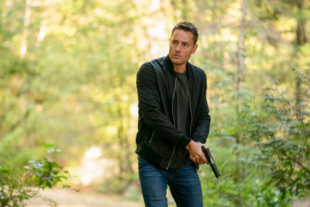 Justin Hartley holding a gun. 