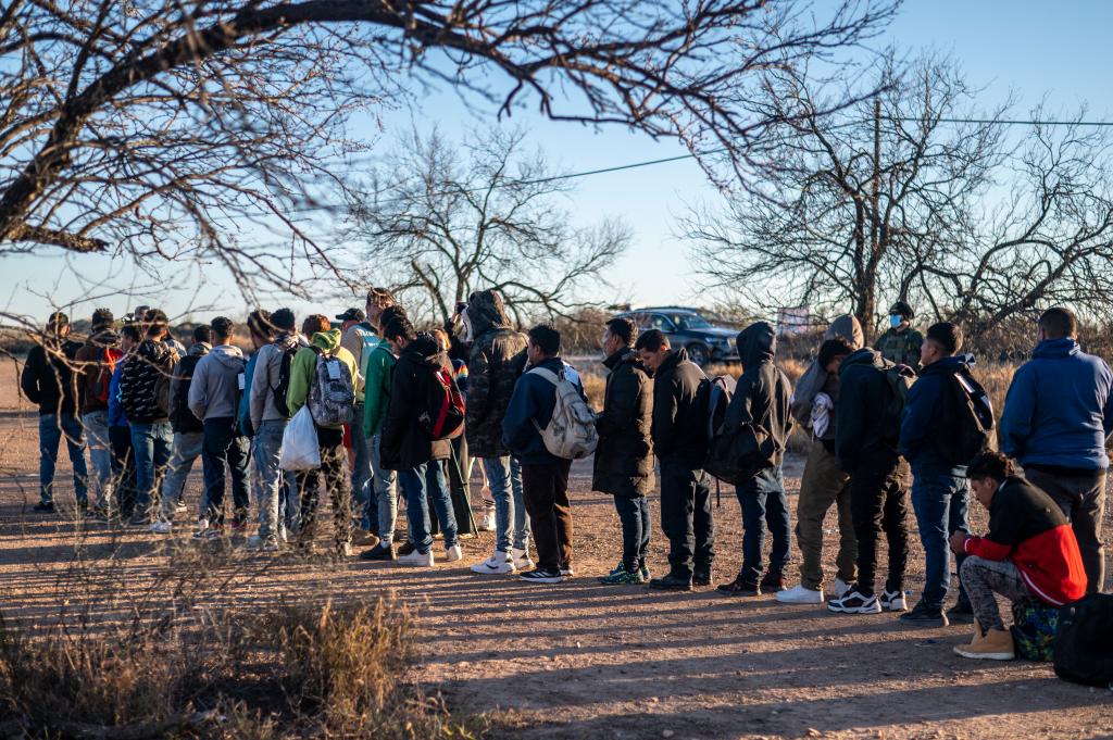 A group of migrants are processed by Border Patrol after crossing the river illegally near the highway on February 4, 2024 outside Eagle Pass, Texas. Eagle Pass, about 20 miles (30 kilometers) from Quemado, has become the epicenter of a prickly conflict between Texas Governor Greg Abbott, a Republican, and the Biden administration. The federal government is suing Abbott for taking control of Shelby Park that includes an access ramp to the river, and for laying barbed wire along the riverbank. (Photo by SERGIO FLORES / AFP) (Photo by SERGIO FLORES/AFP via Getty Images)